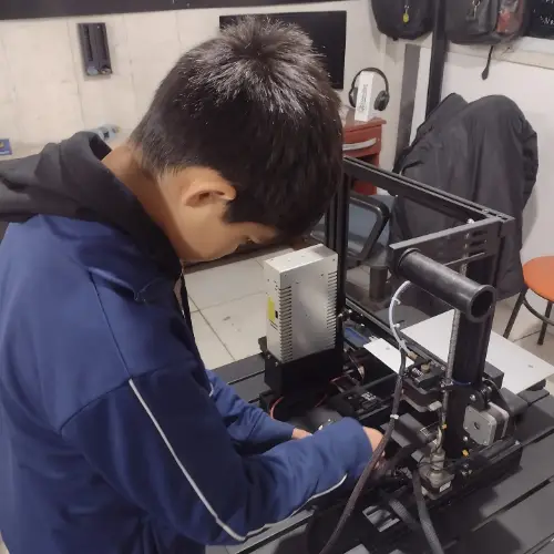 Estudante fazendo manutenção em impressora 3D